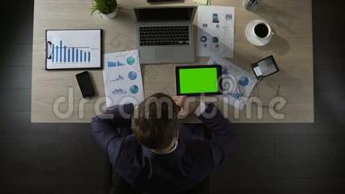 悲伤的商人在绿色屏幕平板电脑上滚动页面，抑郁，俯视