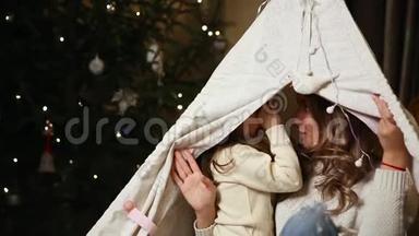妈妈和她的女儿坐在他们家的帐篷里，`对方的耳朵里<strong>诉说</strong>他们对圣诞节的渴望。 这就是