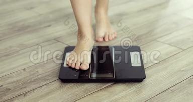 <strong>赤足</strong>的女人在家里用数字现代天平称体重，双脚特写。