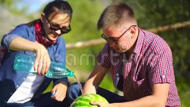 年轻人和女人在河边的森林里野餐吃西瓜。 合上洗西瓜.. 4千克