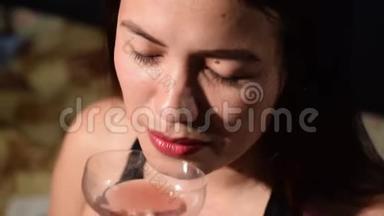 美丽的亚洲拉美裔中年妇女，穿着黑色无袖，在老式玻璃上喝红酒。 黑暗的背景，