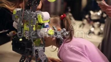 一个小女孩和一个女人在和一个机器人说话。 现代机器人技术。 人工智能。 控制论