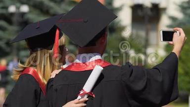 一男一女穿着学术礼服和帽子在毕业典礼上自拍