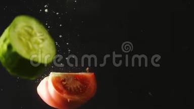 黄瓜和番茄片<strong>落入</strong>水中的黑色背景。 新鲜蔬菜在水中有气泡。 有机有机