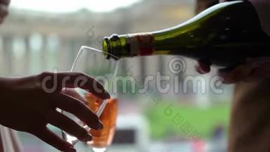 将粉红色<strong>香槟</strong>或起泡葡萄酒从瓶子中倒入<strong>玻璃杯</strong>中。 欧洲城市背景。