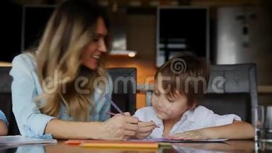 美丽的<strong>妈妈帮</strong>助她的儿子用彩色铅笔画图像。 <strong>帮</strong>助培养孩子`想象力。