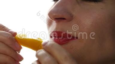 美丽的女人舔和吃一块橙色的白色背景。 健康生活方式的<strong>好食</strong>物。 慢动作