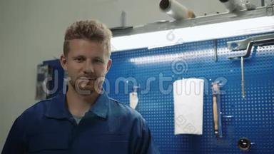 一位<strong>汽车修理工</strong>在修车厂工作时的画像，一个微笑的人在工厂仓库里