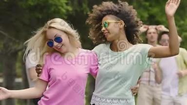 两个女人在公园里和朋友跳舞，拥抱，享受音乐会，<strong>青春洋溢</strong>