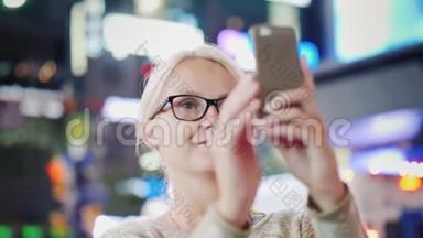 女人是大城市的游客。 带着仰慕的照片用智能手机拍摄。 纽约<strong>时代广场</strong>