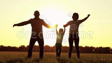 快乐的家庭，爸爸妈妈，和一个<strong>孩子</strong>在户外玩耍。 爸爸和妈妈慢慢地举起手，<strong>抱着孩子</strong>
