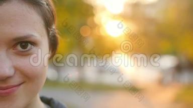 一位可爱的年轻女子在日落时在公园里欣赏秋天的肖像。 布鲁内特在秋天公园的背景