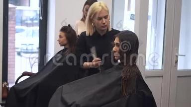 漂亮的女人梳湿头发。 发型师在沙龙里刷女人的头发。 美容师为顾客服务。 专业人员