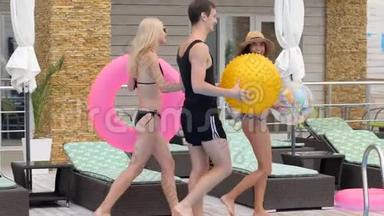在昂贵的度假胜地，穿着带充气戒指的泳衣的青年朋友在暑假陪伴