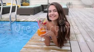 <strong>暑假</strong>期间，可爱的女孩在游泳池附近喝着吸管酒精饮料