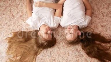 两个十几岁的女孩躺在地板上，头发散落在地板上