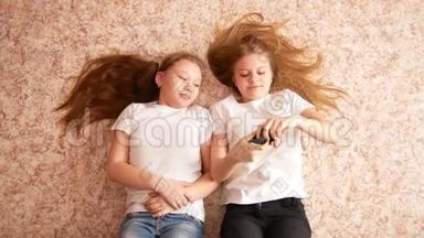 两个十几岁的女孩躺在地板上，笑着拍手机，头<strong>发散</strong>落在地板上。