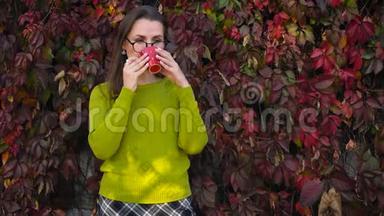 带眼镜的女人在温暖的秋日在户外喝茶或咖啡。 咖啡时间。