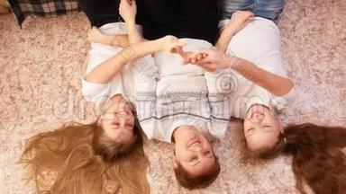 年轻女子和两名少女躺在家里的地板上玩游戏的画像