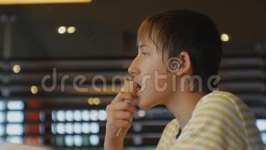 青少年吃快餐。 在快餐店吃冰淇淋锥的青少年男孩的特写镜头。