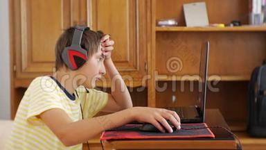 使用笔记本电脑的青少年。 戴着耳机的少年用电脑<strong>游戏鼠标</strong>粘在笔记本电脑屏幕上抓挠