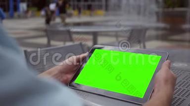 一名男子在市中心商业区的水景附近观看绿色屏幕平板电脑
