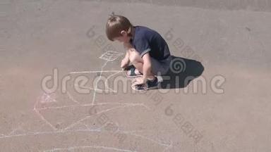 男孩在沥青上用蓝色粉笔画一艘船。 <strong>特写双手</strong>。