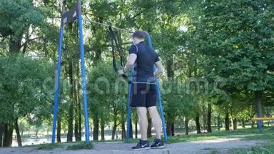 男人开始在夏季公园的健身圈上做拉力运动。 4K慢动作镜头
