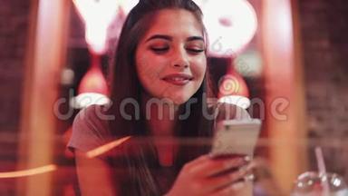 年轻女子坐在<strong>酒吧</strong>里，喝着利曼德，用她的智能手机旁边的<strong>霓虹灯酒吧</strong>标志。 享受夜生活的女人