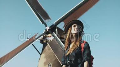 旧风车附近的女旅行者肖像。 不可思议的<strong>电影</strong>低角度。 在农场磨坊前戴帽子的女孩。 4K
