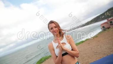 年轻女子在黎明或日落时在岩石上靠近海洋练习瑜伽。 冥想。 把她关起来。 相机旋转360