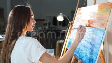 一位女艺术家在车间里用油画颜料在画布上作画。