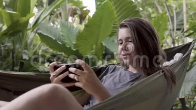 女人坐在吊床上玩手机游戏