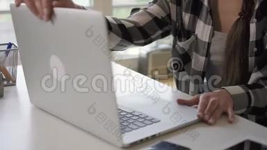 年轻的企<strong>业主</strong>女士打开笔记本电脑，坐在明亮的房间里的家庭工作场所。