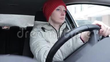穿着冬装戴着橙色针织帽子的女人在冬道上开车