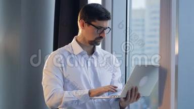 一个集中的商人在笔记本电脑上打字，看着窗外。