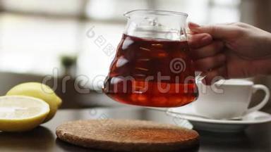 茶被倒入玻璃透明茶杯中。 一杯茶。 糖果，热茶和茶壶.. 陶瓷茶壶和玻璃茶杯