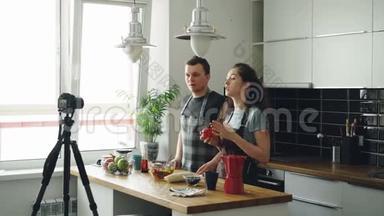 在家的厨房里，用数码相机拍摄一对迷人的情侣，录下有关烹饪美味沙拉的视频食物
