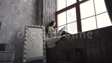 灵感女艺术家，穿着靠近窗户的裙子。 迷人的黑发女孩坐在艺术的窗台上