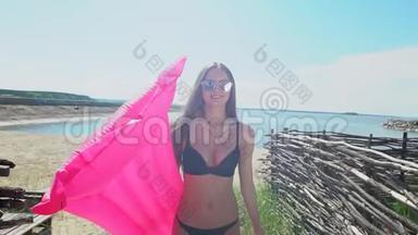 美丽的年轻<strong>比基尼</strong>女人拿着粉红色的气垫。 <strong>比基尼</strong>女孩在夏天在热带放松。 的概念