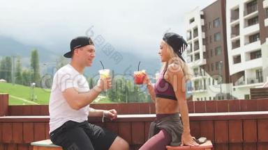 紧张的锻炼后，一对活泼的夫妇坐在咖啡馆里享受新鲜饮料。