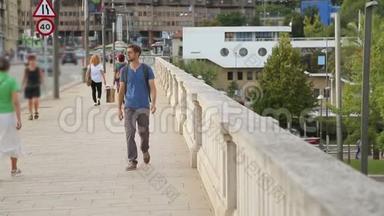 年轻男子背着背包走过大桥，看着城市<strong>地标</strong>