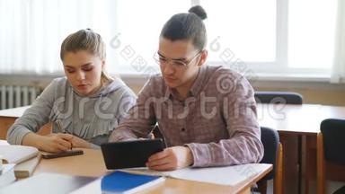 年轻的大<strong>学生</strong>们一起使用平板电脑，<strong>讨论</strong>准备考试的项目，坐在桌旁