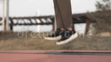 穿着卡其裤和<strong>运动</strong>鞋在公园<strong>蹦床</strong>上跳跃的女人腿