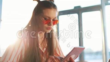 年轻迷人的女士戴着红色太阳镜，在咖啡馆里<strong>使用</strong>带有触摸屏的平板电脑。 <strong>机场</strong>或<strong>机场</strong>的美女