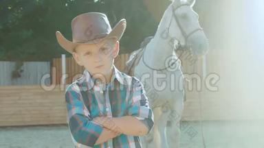 小牛仔的肖像，双手交叉，在阳光下靠近马。 慢慢地