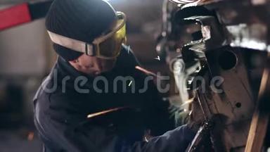 带防护眼镜的工人用圆锯打磨金属结构。