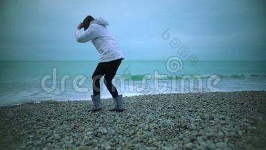 年轻女子在沙滩上散步，怕在海水中弄湿鞋子，溅起<strong>浪花</strong>