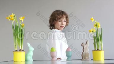 复活节传统。 男孩偷了一个复活节彩蛋，幼稚的恶作剧。 餐桌旁可爱的可爱小学生，装饰复活节