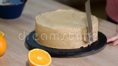 厨师把蛋糕层贴在奶油上。 烹饪分层蛋糕。 做分层馅饼。 巧克力蛋糕层